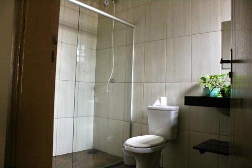 a bathroom with a toilet and a glass shower at Chacara Mariana in Olímpia