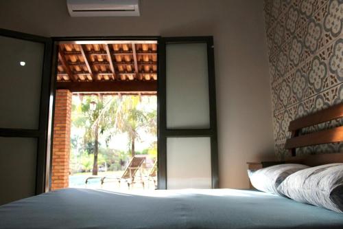 a bedroom with a bed and a window with a patio at Chacara Mariana in Olímpia
