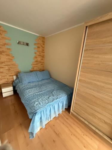 a small bedroom with a bed and a wooden floor at Apartament MIRO in Ostróda