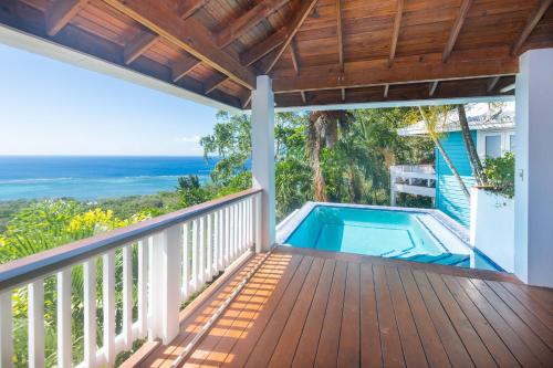 a balcony with a swimming pool and the ocean at Top Ridge Views home in Roatán