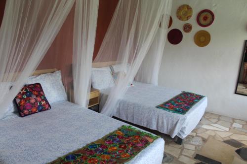 a bedroom with two beds with curtains at Hotel Kocai Izamal in Izamal