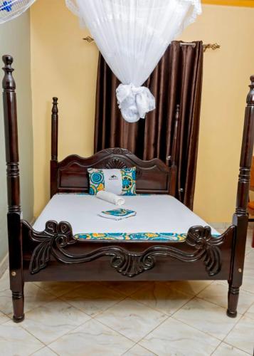a bed with a wooden frame with a canopy at Peak Motel in Kasese