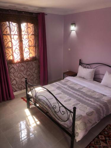 a bedroom with a bed and a window with red curtains at Hotel El Maghreb in Constantine