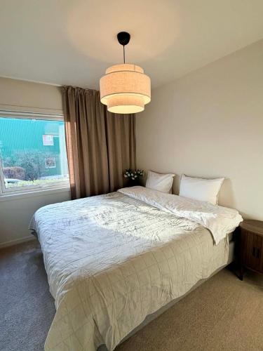 a bedroom with a large bed and a chandelier at Flott 4-roms leilighet til leie in Trondheim