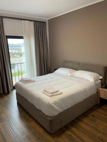 a bedroom with a large bed with a large window at Clean City Agrotourism in Durrës
