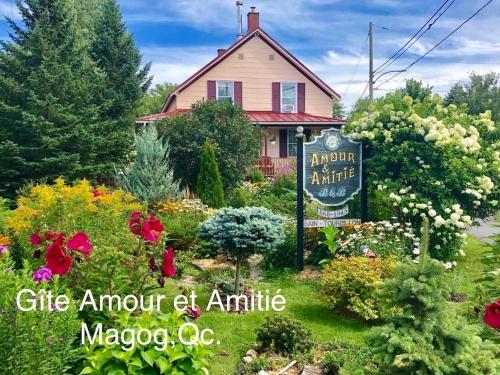 a house with a sign in a garden at À Amour et Amitié in Magog-Orford