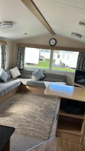 a living room with a couch and a clock in a van at Crichtons Caravan at Haven Seton Sands in Port Seton