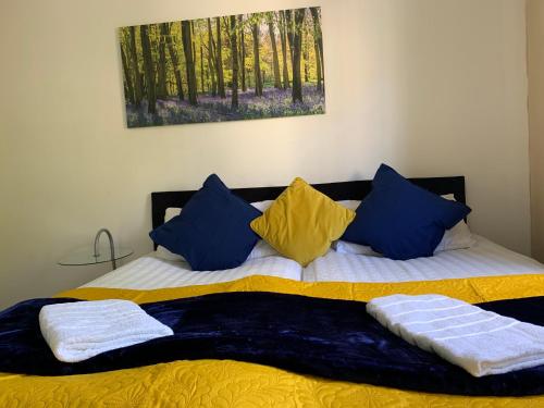 a bed with blue and yellow pillows on it at 2 Bedrooms Modern Central London Apartment, Full Kitchen, 5 minutes Tube Station in London