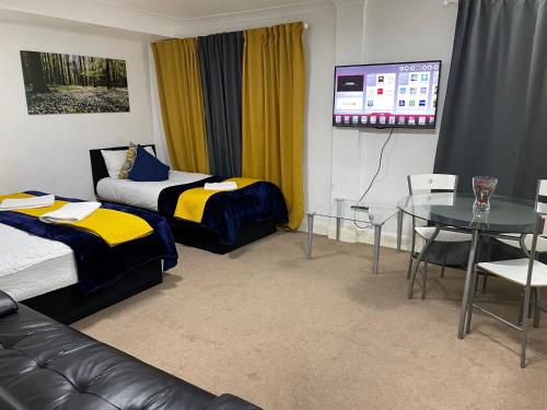 a room with two beds and a table and a tv at 2 Bedrooms Modern Central London Apartment, Full Kitchen, 5 minutes Tube Station in London