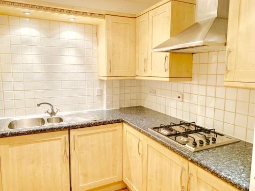 a kitchen with wooden cabinets and a sink and a stove at 2 Bedrooms Modern Central London Apartment, Full Kitchen, 5 minutes Tube Station in London
