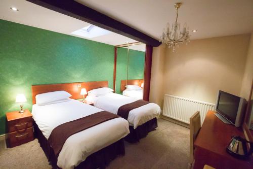 a hotel room with two beds and a mirror at The Peacock Townhouse Hotel Kenilworth - Warwick in Kenilworth