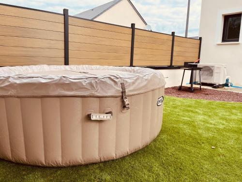 a large tub sitting on the grass in a yard at Maison moderne 3 chambres SPA-jacuzzi mai-septembre in Cerelles