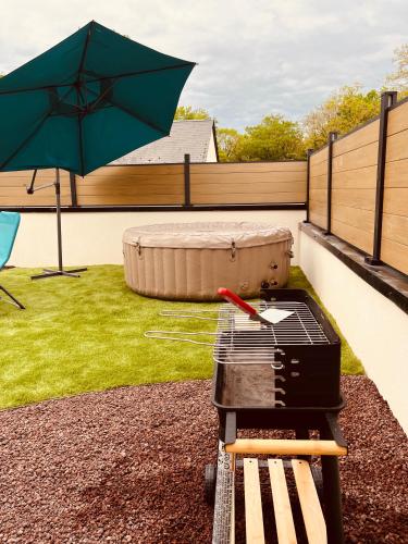 a grill with a green umbrella on a patio at Maison moderne 3 chambres SPA-jacuzzi mai-septembre in Cerelles