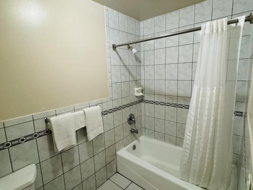 a bathroom with a shower and a tub and a toilet at Imperial Inn & Suites in Norwalk