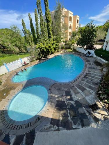 a large swimming pool with a stone path around it at Pristine Home - Cozy Luxury Residence in Mtwapa