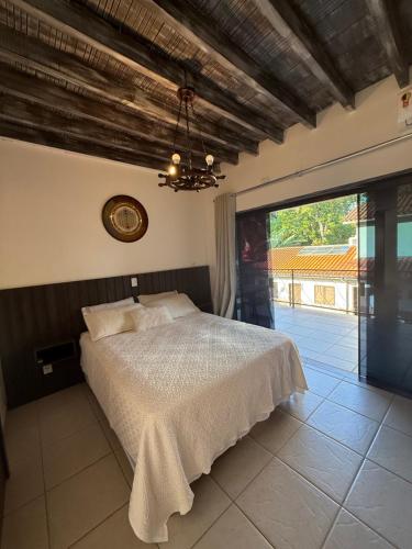 a bedroom with a bed and a large window at Pousada Bahan Suites privativas - ideal para Casais in Ubatuba
