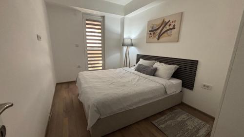 a bedroom with a bed with white sheets and a window at M&M Cozy Apartment-Free Parking in Skopje