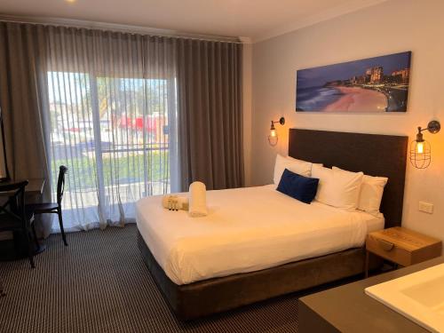 a hotel room with a bed and a large window at Merewether Motel in Newcastle