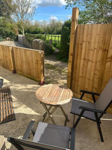 a patio with a table and chairs and a fence at The Hayloft in Oaksey