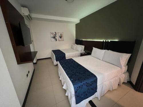 a hotel room with two beds and a flat screen tv at Mai Suites Apart Hotel in Santa Cruz de la Sierra
