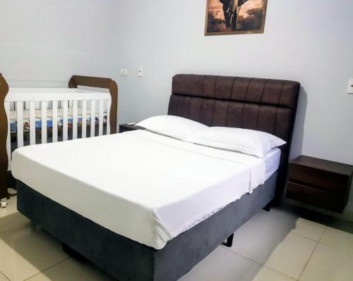a bed with white sheets and a brown headboard in a bedroom at Casa Paraíso Piscina Aquecida e Pet Friendly in Sinop