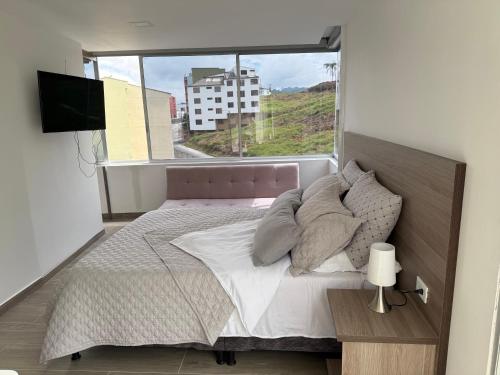 a bedroom with a bed and a large window at Casa Aurora in Manizales