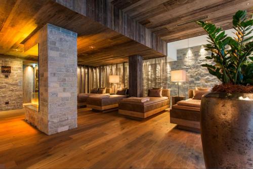 a living room with couches and a stone wall at Alpenhotel Ischglerhof in Ischgl