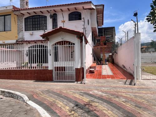 a white house with a gate on a street at Rincón de Paz y Tranquilidad in Ambato