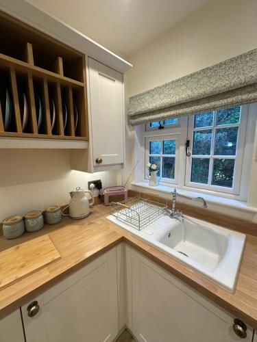 a kitchen with a white sink and a window at Hollylea Cottage - New Forest in Godshill