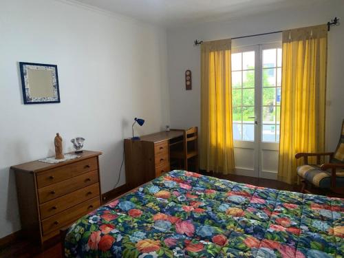 a bedroom with a bed and a dresser and a window at Charming Blue House in Furnas