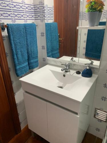 a bathroom with a white sink and a mirror at Charming Blue House in Furnas