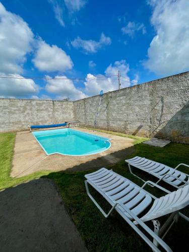 a swimming pool with two lounge chairs next to a wall at Chácara Lobos in Sorocaba