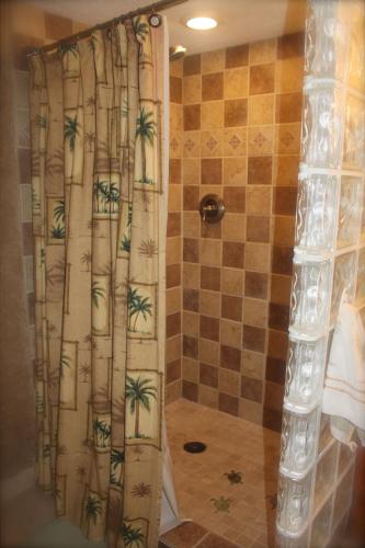 a shower with a curtain with palm trees on it at Unique Artist Home Steps from the Ocean in Kihei