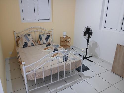 a bedroom with a white bed and a fan at Maison Hibiscus in Petit-Bourg