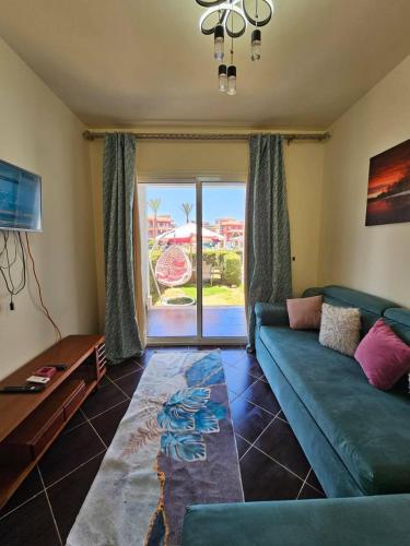 a living room with a green couch and a sliding glass door at بورتو مطروح - القبطان in Marsa Matruh