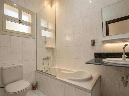 a white bathroom with a toilet and a sink at Soly Apartments in Hurghada