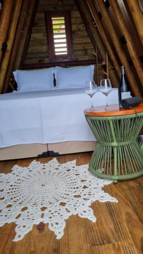 a bedroom with a bed and two wine glasses on a table at Cabana Redonda Beach in Icapuí