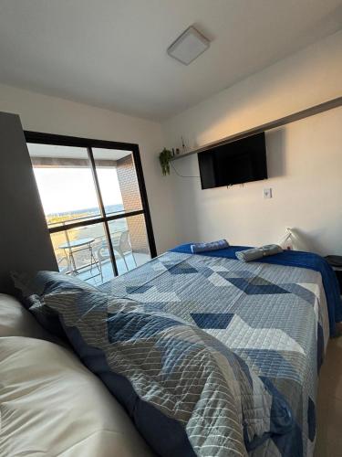 a bedroom with a bed and a flat screen tv at Studio nascente na Pituba in Salvador