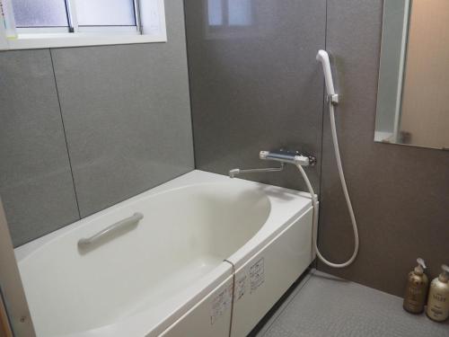 a bathroom with a bath tub with a shower at Sudomari Minshuku Friend in Yakushima