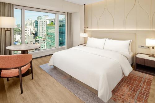 a bedroom with a large white bed and a table at The Westin Seoul Parnas in Seoul