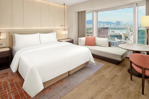 a bedroom with a large white bed and a table at The Westin Seoul Parnas in Seoul