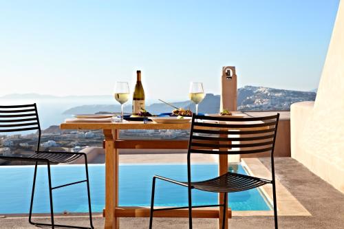 a table with wine glasses and chairs on a balcony at Voreina Gallery Suites in Pyrgos