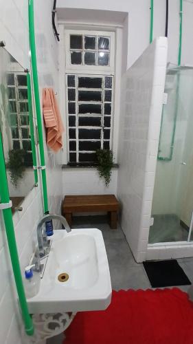 a bathroom with a sink and a shower and a window at Vila Santa Eulália Hostel in Pelotas