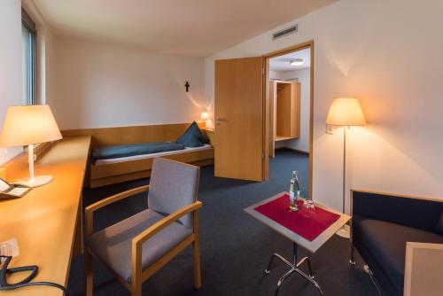 une chambre d'hôtel avec un lit, une table et des chaises dans l'établissement Tagungshaus Himmelspforten - Self Check-In, à Wurtzbourg