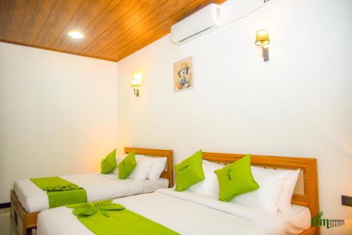 two beds in a room with green pillows at Om Hotel in Unawatuna
