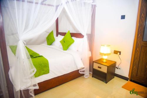 a bedroom with a white bed with green pillows at Om Hotel in Unawatuna