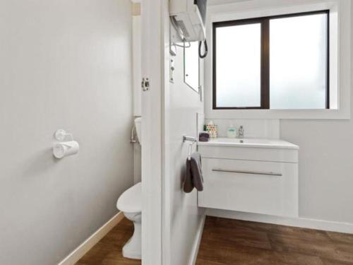 a white bathroom with a sink and a window at Oakleigh Motel in Gore
