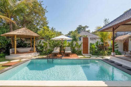 a swimming pool with chairs and umbrellas next to a house at Sicilia Villa - Ubud Pool Stay with Open-Air Bath & Gazebo in Ubud