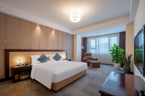 a bedroom with a large white bed and a desk at Jin Jiang West Capital International Hotel in Xi'an