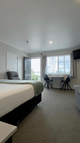 a bedroom with a large bed and a desk and chairs at BK's Pohutukawa Lodge in Whangarei